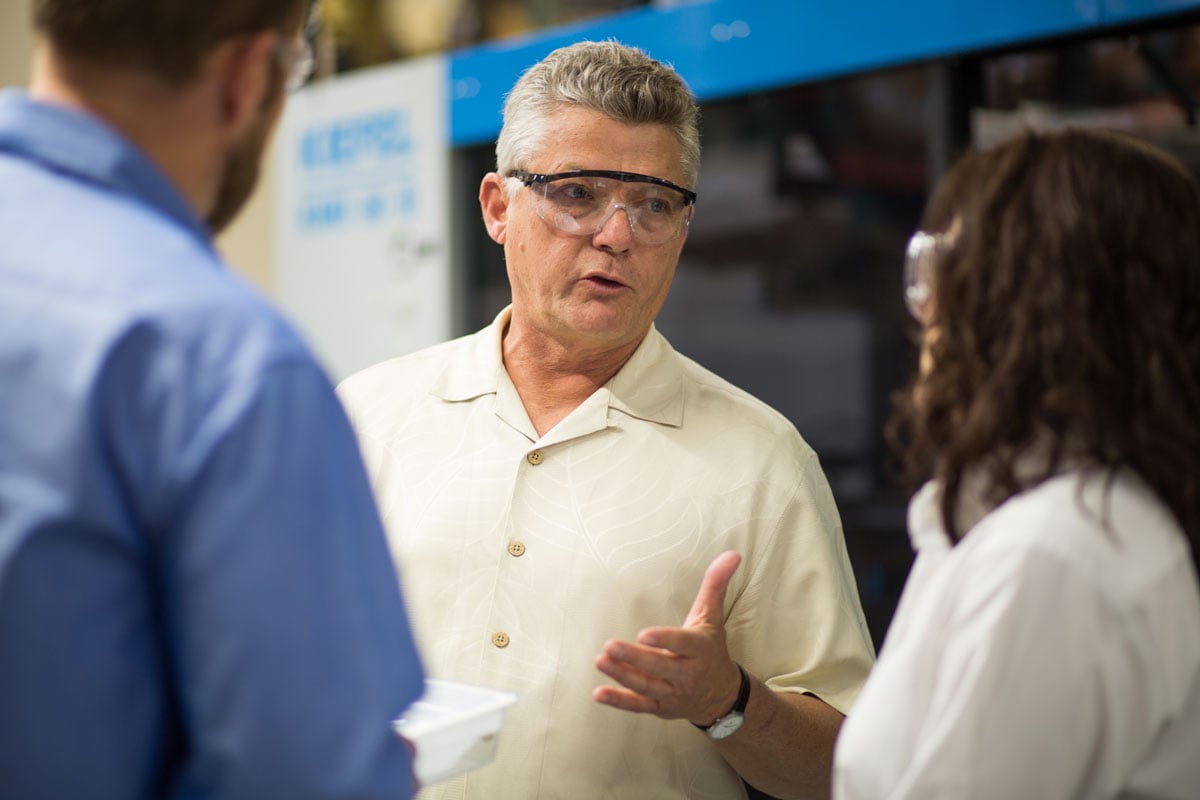 Tony Beyer, CEO of Tek Pak Inc., discussing production with his team in safety goggles