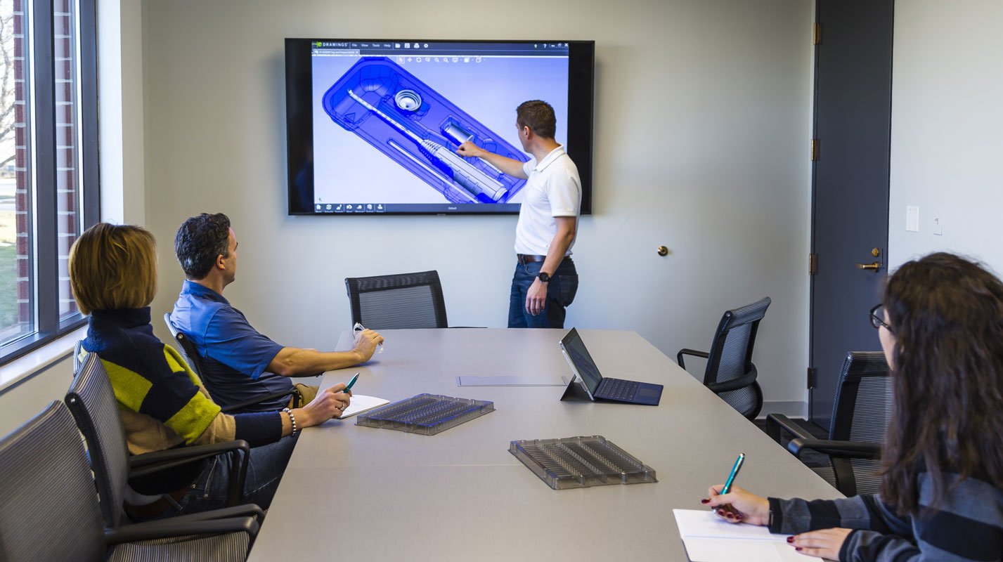 Tek Pak Conference room with four team mates discussing a presentation