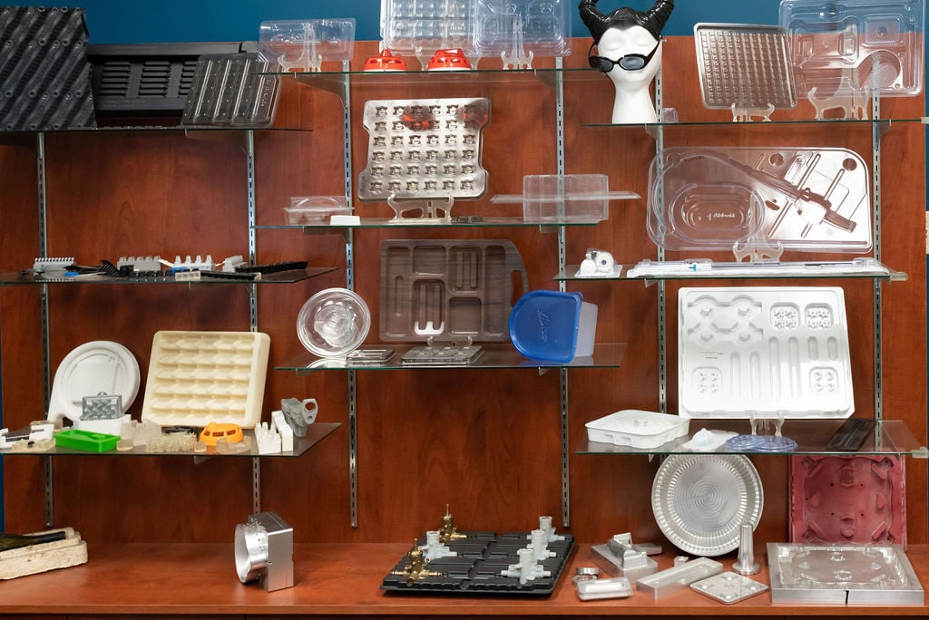 A shelf full of various thermoformed tools, components, and fiber molded pieces from Tek Pak. Respective plug assists and molds too