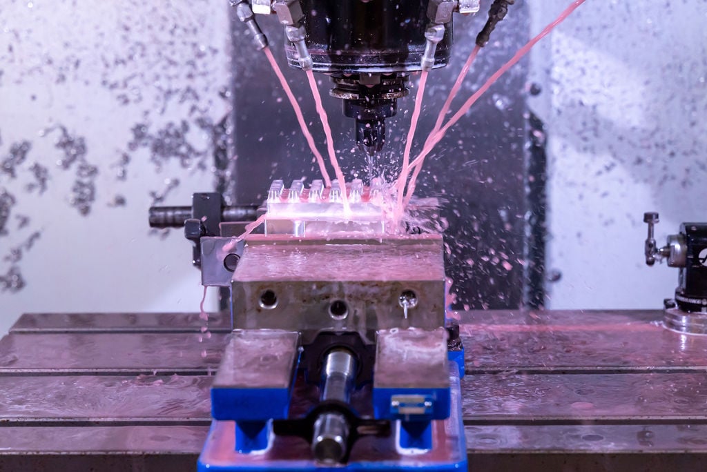 Close up of a CNC machine dousing a metal alloy with EDM fluid