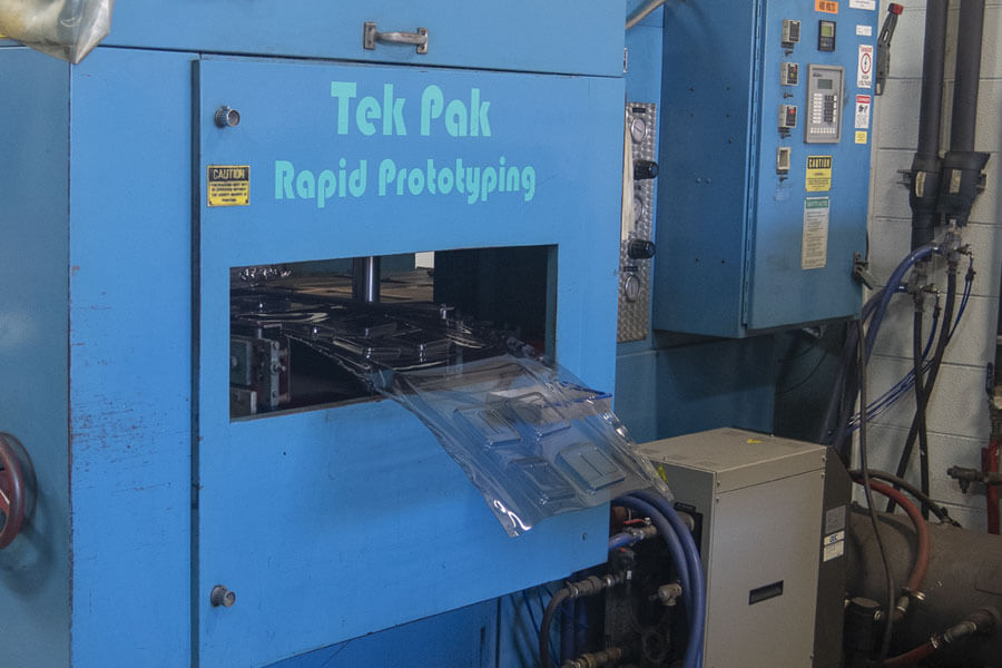 Royal blue Tek Pak machine feeds out plastic material