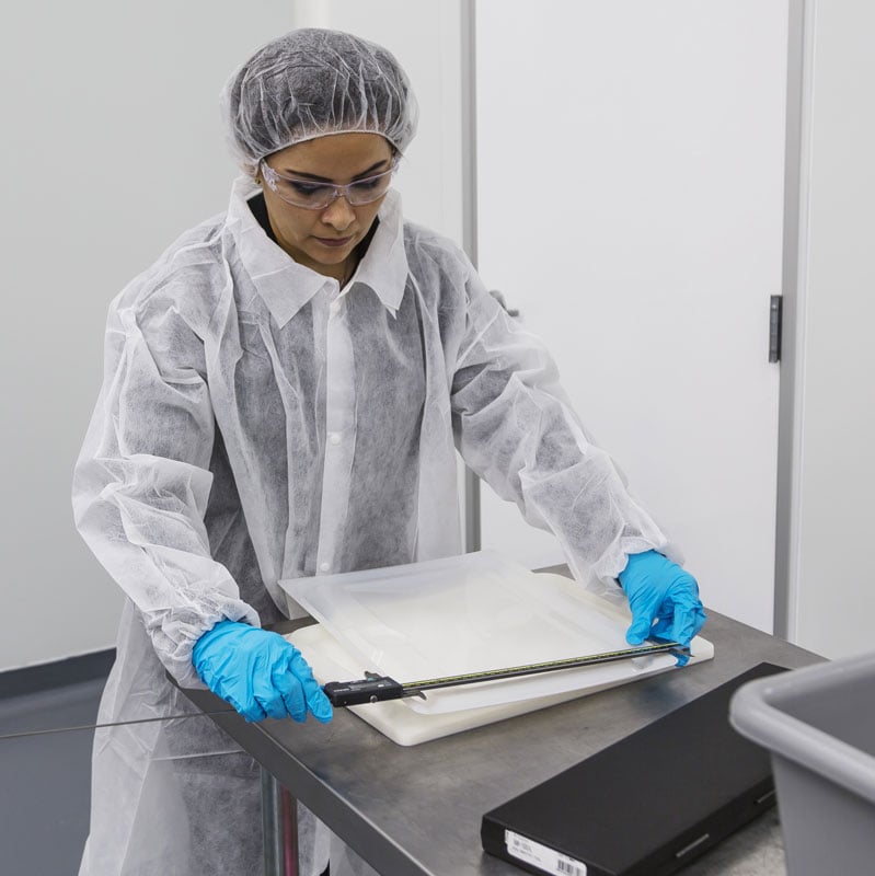 Engineer in protective outfit uses measuring too to check thermoformed plastics