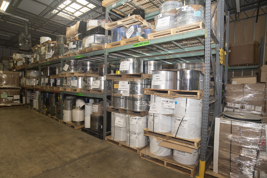 Supply shelving unit with white and chrome drums stacked on pallets
