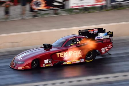 tek pak funny car in red driving on drag strip