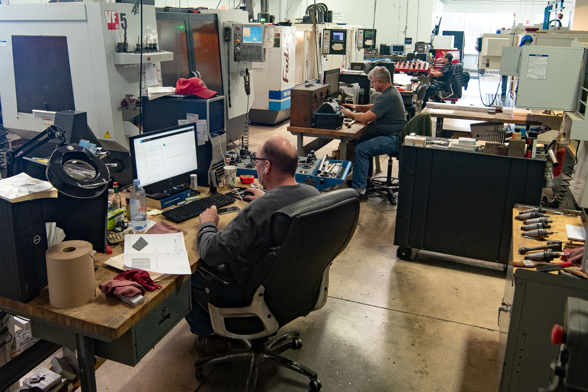 Two thermoforming engineers at Tek Pak analyze production metrics from the office.